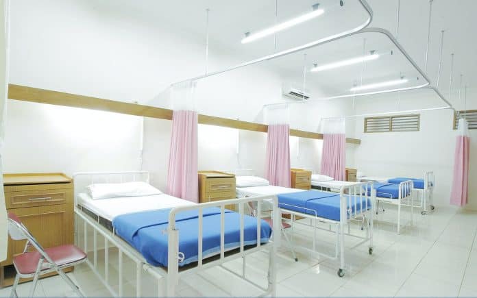 Four hospital beds lined up in a ward