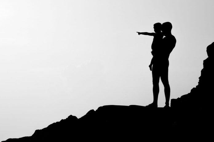 Father holding a young boy while standing on a rocky precipice
