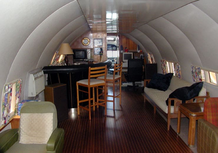 Interior of the plane boat, with several chairs, a computer, and a bar.
