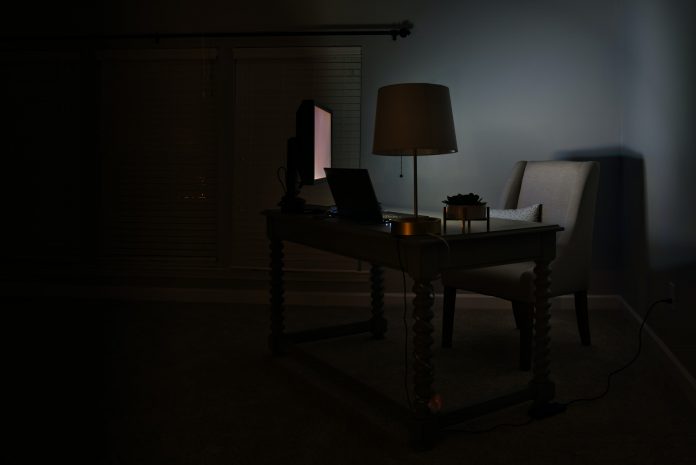 Dark corner of room with computer desk, computer screen lit up