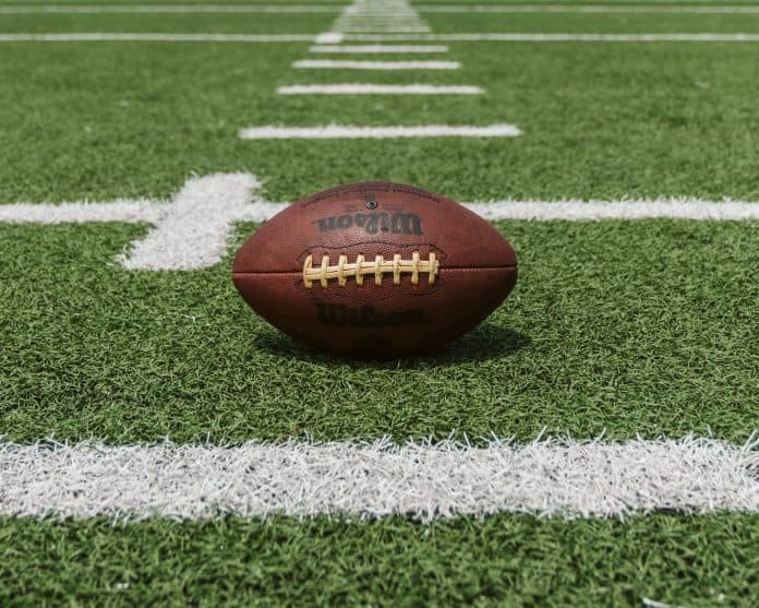 Football sitting between yard lines on a field