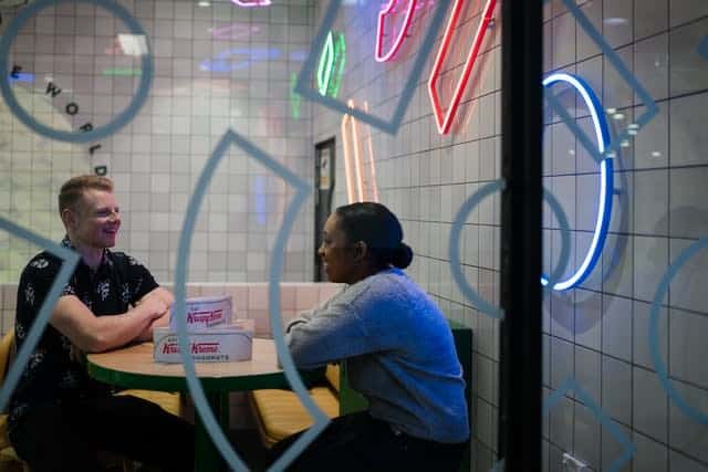 Man and woman sitting inside donut shop, talking