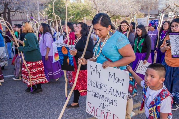 Group of Indigenous women marking, holding signs and staffs