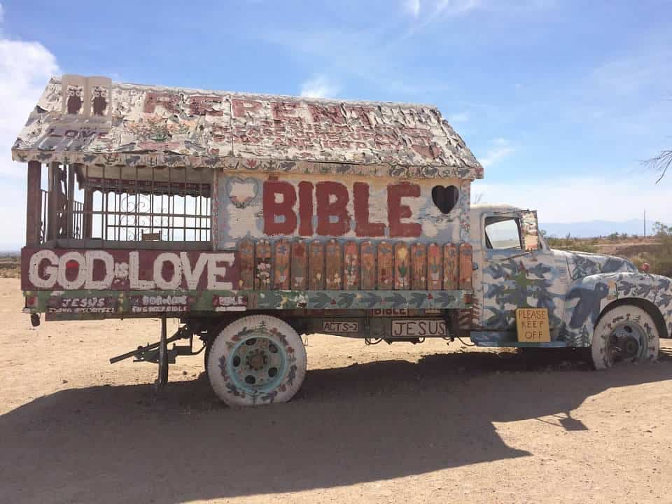 Truck with covered bed covered in painted words about the bible, god is love
