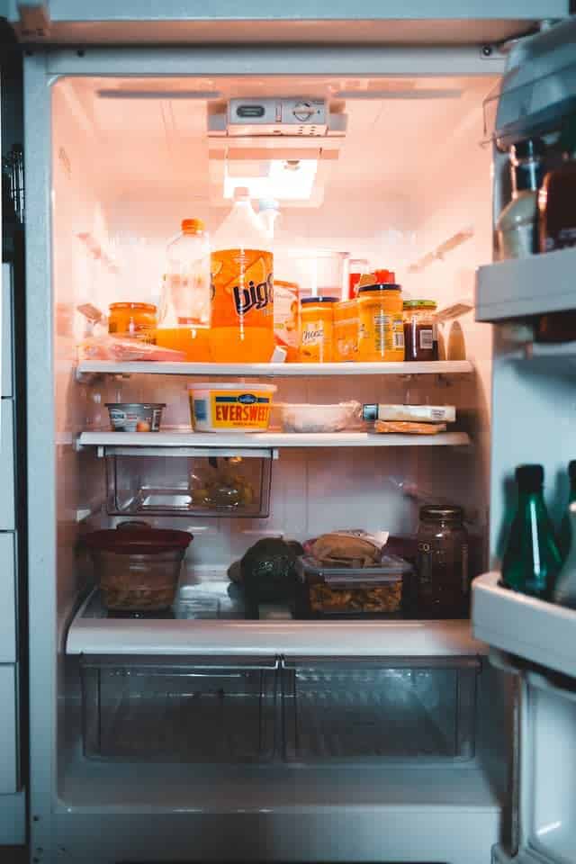Fridge with leftovers, soda, and jars on shelves