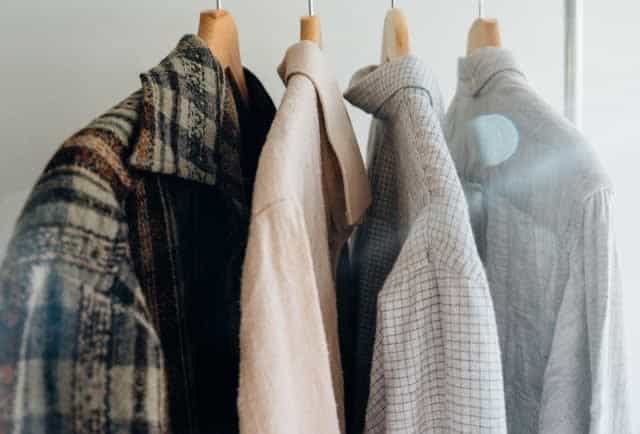 Side view of four, men's shirts hanging from hangers