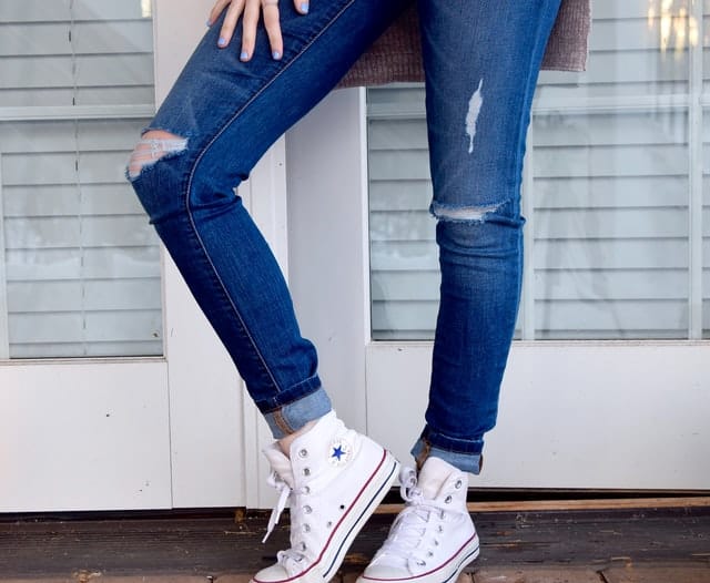 Person standing with jeans on, and bright white shoes