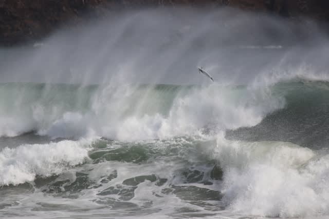 Choppy waves and water spray, with a surf board in the air