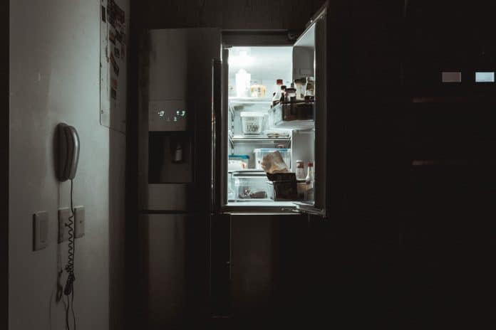 Kitchen, at night with no lights on. A refrigerator with one side door open.