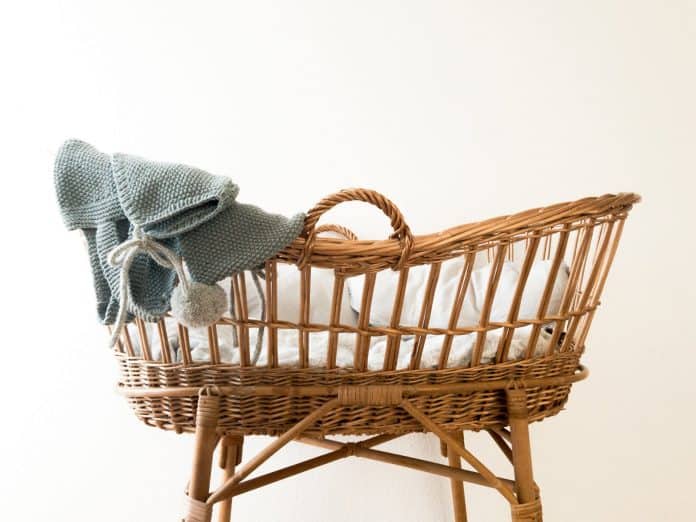 wooden baby bassinet with a sweater on the edge