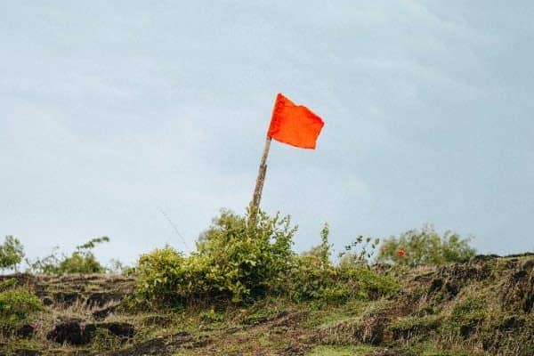 Red flag tied to a brach on a mossy and brush covered hill