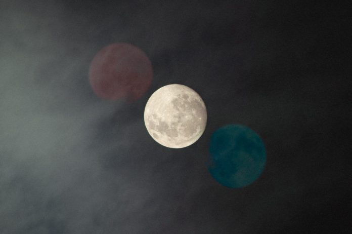 Photo of the moon, with two copy images of it on either side. One blue one red