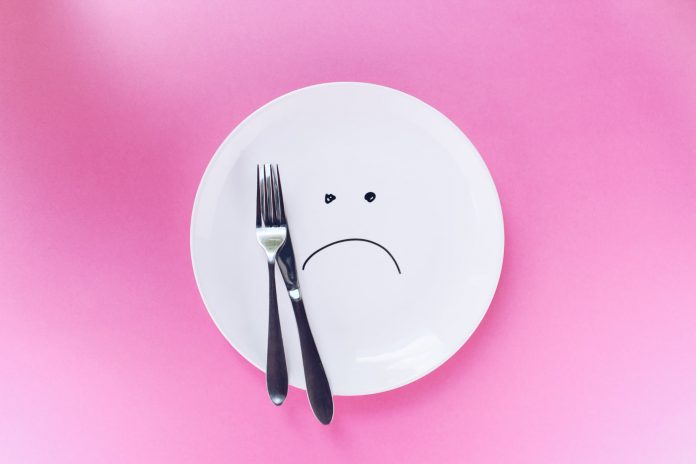 Pink background, white plate, with frowny-face drawn on it
