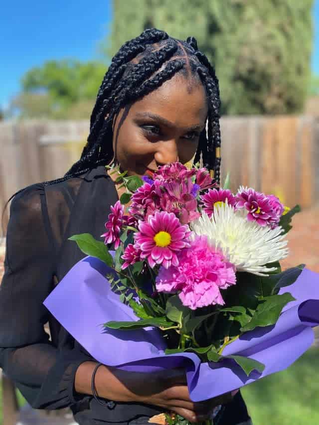 Woman outside, holding and smelling big bouquet of flowers
