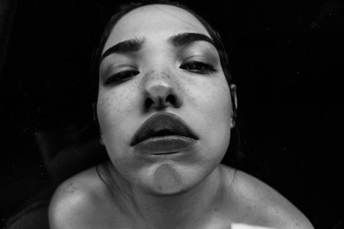 Woman with lips and chin pressed on glass in front of camera